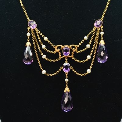 14K Yellow Gold Amethyst and Pearl Chandelier Style Necklace: A 14K yellow gold amethyst and pearl chandelier style necklace. This necklace features briolette amethyst drops among pearl studded chains with oval amethyst accents.