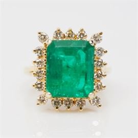 14K Yellow Gold 4.73 CTS Emerald and Diamond Ring: A 14K yellow gold 4.73 cts emerald and diamond ring. The ring features a center emerald surrounded by prong set round brilliant cut diamonds in a basket setting.