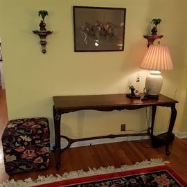 Sofa table, tapestry-look upholstered ottoman, monkey & palm themed candlesticks on brackets framing an horse racing artwork