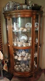 Antique Reproduction Curved-Front Curio Cabinet
Very fine. Beveled edges, elegantly carved hinged backboard and paw-style feet. Solid sturdy wood. Unique curved front. 3 glass shelves within. 2 side-facing doors. Light fixture in top of unit. Overall very good condition. Measures 79"tall to top of backboard (70"tall to top surface) x 42"wide x 19"deep.