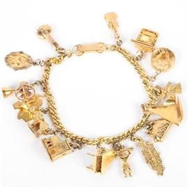 Yellow Gold Bracelet with Fifteen Charms: A yellow gold bracelet with fifteen charms of various fineness ranging from 9K – 18K. The banjo, horse and carriage, body builder, purse, sailboat, typewriter, and cello are all made of 9K yellow gold. The religious medal, fan, church, piano, Tobago, windmill, and drum are made of 10K yellow gold. The Venezuela charm is made of 18K yellow gold.