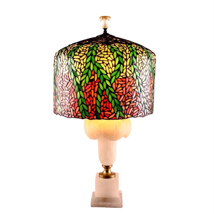 Large Italian Art Nouveau Alabaster Lamp with Slag Glass Mosaic Shade: An Italian alabaster Art Nouveau lamp, with a large and elaborate slag glass mosaic shade. This unique lamp sits on a pedestal base; boasting of a carved floral design, double sockets, and matching original alabaster finial. The intricately made, lead and slag glass mosaic shade, boasts of a vibrant palette of green, orange, pink, peach, blue and more, in a vine and petal design; withan open-work, bronze top. Socket and cord are not original to piece. Inscribed to the base “Made in Italy”.