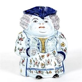 Antique French Majolica "Fat Boy" Toby Pitcher: An antique French majolica “Toby Fat Boy” pitcher. This Toby is featured in 18th century French garments, with floral vestments in a palette of cobalt blue, orange, red, yellow and green. Numbered to the underside 60/1691 with artists mark.