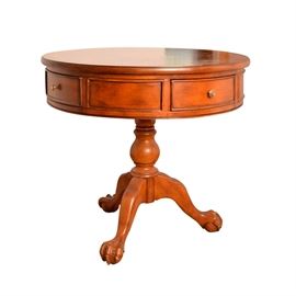 Chippendale Style Drum Table: A Chippendale style drum table. This circular table features multiple veneers including mahogany, cherry and walnut in a figural design medallion framed in a border. The top rests above apron sides including four drawers with bowed panel fronts and knob pulls as well as framed panels between the drawers. The top rests on a turned baluster base including ball, ring and trumpet turnings rising up on cabriole legs ending in claw and ball feet.