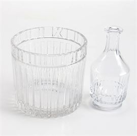 Tiffany & Co. Ice Bucket and Baccarat Decanter: A Tiffany & Co. ice bucket and Baccarat decanter. This collection of two items includes an Atlas pattern cut crystal ice bucket with Roman numerals and vertical lines. This piece is acid etched “Tiffany & Co.” to the underside. Also included is a Baccarat crystal decanter that is marked “Baccarat” to the underside.