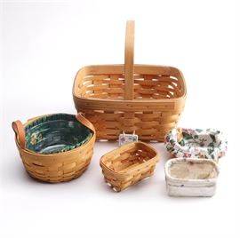 Longaberger Baskets: A collection of Longaberger baskets. This collection includes a rectangular wooden basket with a wooden handle, a round basket with cloth and plastic liners and two leather handles, and two small rectangular baskets with removable cloth liners. All baskets are marked “Longaberger Baskets® Handwoven Dresden, Ohio USA”.