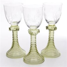 Frosted and Colored Wine Glasses: A grouping of matching wine glasses. These pieces feature an ascending base and neck with an embossed ripple pattern with a tumbler chalice that features frosted floral patterns. There are no maker’s marks present on these pieces.
