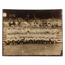 Original 1919 Reds Photo: An original first generation 1919 Cincinnati Reds team photo. The photographer’s stamp is on the back, “J. R. Schmidt 1557 St. Charles Place, Hyde Park Cincinnati, O”. There is a written notation on the back, done in black fountain pen that has the first and last names of the players and “Official Group Penant Winning Reds”. The players are in uniform, sitting on some wood bleachers on the field. The stands behind the players has fans arriving for the game. The photo is not dated per se, but the notation stating that it’s the “Penant Winning Reds” dates it, as the Reds only pennant win of this era was in 1919. The names listed (as they are written on the back) are: “Back Row – Sherwood Magee, Eddie Roush, Morris Rath, Hod Eller, Harry Sallee, Eddie Gerner, Ray Fisher, Jimmy Ring, Heinie Groh, Rube Bressler, Hank Schreiber and Roy Mitchell Front Row – Jake Daubert, Charley See, Walter Ruether, Pat Moran, Bill Rariden, Nick Allen, Ivy Wingo, Greasy Neale, Pat Du