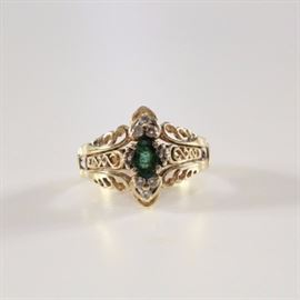 10K Diamond and Emerald Ring: A 10K diamond and emerald ring set. The center ring features an emerald set between filigree shoulders, while the jacket has diamonds flanking the top and bottom of the emerald on pierced filigree shoulders.