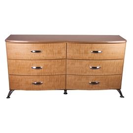 Contemporary Faux Maple Dresser by Ashley Furniture: A contemporary faux maple dresser by Ashley Furniture. The dresser is marked to the back “Signature Design by Ashley Furniture Industries, Inc.” and is model number B250-31. It is made of engineered wood with a laminate surface, featuring an attractive faux maple finish. The dresser has double bow fronts, with six drawers, each fitted with polished chrome finished handles. The front of the dresser top is accented with rounded, chrome metal trim, and the dresser rests on curved, chrome finished metal legs. This item matches item 17DEN021-009 and 17DEN021-010. Please note, this item is located on an upper floor.