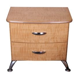 Replicated Maple Grain Nightstand by Ashley Furniture: A contemporary faux maple nightstand. The contemporary nightstand is made of engineered wood, with a laminate surface, featuring a faux maple wood grain finish. The nightstand has a rectangular top with rounded corners on the front, accented with chrome metal trim. Below are two drawers, each fitted with chromed metal handles. The night stand rests on splayed chrome metal legs. It is marked “Signature Design by Ashley Furniture”, and matches items 17DEN021-009 and 007. Please note, this item is located on an upper floor.