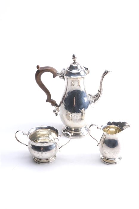 J. Wagner & Son Sterling Silver Coffee Service: A sterling silver coffee service by J. Wagner & Son. This set includes a coffee pot with a hinged lid and scrolled wooden handle and an open sugar bowl and creamer set. The coffee pot is etched “Aunt Sally’s C.S.B.C. of N.E.” to the front and the sugar bowl and creamer are etched “C.S.B.C. of N.E.” to the front. The underside of each is stamped “Sterling 2155” alongside the J. Wagner & Son maker’s mark. The total approximate weight, excluding coffee pot with wooden handle, is 9.235 ozt.
