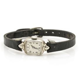 Hamilton 14K White Gold Wristwatch: A Hamilton 14K white gold wristwatch features a rectangular care with black hour markers and hands on a white dial and a classic leather band.
