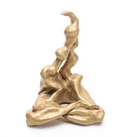 Abstract Clay Figurative Sculpture: An abstract clay figurative sculpture. This piece, painted in a semi-matte gold tone, appears to be modeled after a figure seated with its legs crossed. The upper portion of the piece is made up of two bulbous curving lines. This sculpture has no markings to indicate the artist.
