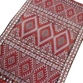 Vintage Hand Knotted Moroccan Prayer Rug: A vintage, hand knotted Moroccan prayer rug. This wool rug features diamond central medallions in cream, green, yellow and scarlet on a burgundy field filled with geometric designs. Bands of repeating geometric designs flank either end, leading to additional diamond medallions and brief compound borders. The major, unresolved diamond patterned borders are surrounded by colorful guard borders. This rug has natural wool fringe to one side and is unmarked.