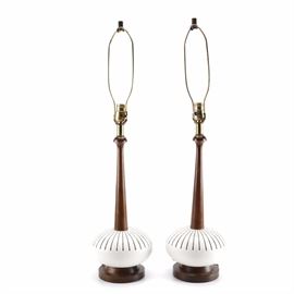 Vintage Ceramic and Wood Table Lamps: A pair of vintage ceramic and wood table lamps. This selection of two single socket table lamps include bronze tone finials, harps, and sockets, tapered wood columns, oval off white ceramic accents, and round wooden bases. No visible maker’s marks.