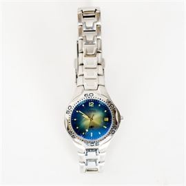 Fossil Blue Stainless Steel Wristwatch: A Fossil Blue stainless steel watch. This watch is composed of a stainless steel band with a blue and green tone face. It is marked Fossil Blue All Stainless Steel 100 Meters/330 Feet Water Resistant on the back. The original tin box is included.