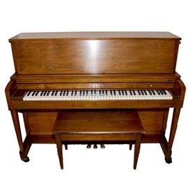 Baldwin Hamilton Upright Piano: A Baldwin Hamilton upright piano. This piano is solid wood with a full set of keys and pedals. It has wheeled feet and a matching bench. The bench seat is hinged for extra storage space. It is marked Baldwin Hamilton.