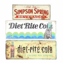 Vintage Cola Advertising Signs: A pair of vintage Diet Rite Cola metal advertising signs including a sign with blue, teal, and green waves underneath a bottle of Diet Rite Cola, and a yellow striped sign with red, black, and teal lettering which reads, “enjoy sugar-free diet-rite cola” and “only 1 calorie per serving”. Also included is a white metal sign with red lettering which reads, “Ask for Simpson Spring Beverages”.