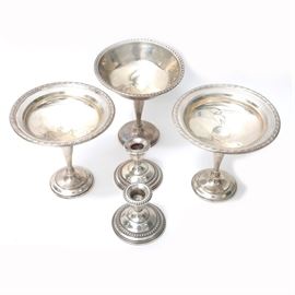 Weighted Sterling Tableware Featuring Watrous: A selection of weighted sterling. This is comprised of two pierced edge compotes by Watrous Mfg Co. and a Ellmore Silver Co. compote with laurel leaf trim. The two candle holders are by Empire Silver Co.
