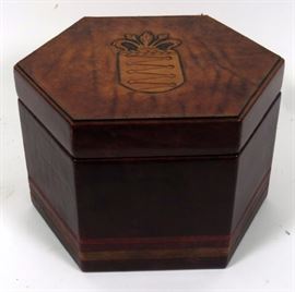 Lot#202, HEXAGONAL, LEATHER CLAD, HAT BOX, C19TH C, H 8 1/2", DIA 12"A hexagonal leather clad hat box with a tooled coat of arms on the hinged lid. Opens to a black velvet lined interior.