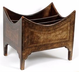Lot#207, MAITLAND - SMITH, WOOD AND LEATHER CLAD MAGAZINE RACK, LATE 20TH C, H 16", W 18", D 13"A tooled leather clad wood magazine rack. Having parabolic shape to top edges, with two partitions, contoured brackets at the square tapered legs. Black painted underside.