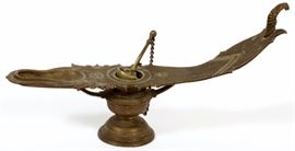 Lot#293, CHINESE RAISED RELIEF BRONZE OIL LAMP L 17" Set on an urn form base with an oil reservoir with ladle and chain. Engraved design with a dragon form head at one end and a small depression for oil at the other.