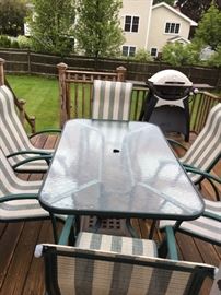 out door dining table with 6 chairs and a grill