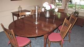 Cherry table with four leaves and drop ends. Six plank seat kitchen windsor chairs.