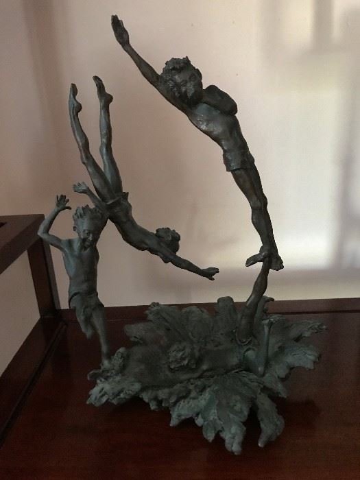 Whimsical bronze statue of three boys diving and playing in the water