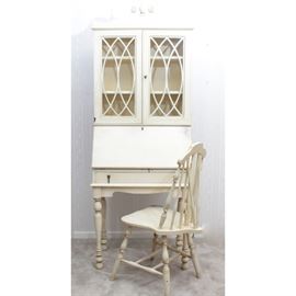 Antique Secretary Desk With Hutch and Chair: An antique painted wooden secretary desk with attached hutch and matching chair. This slant front secretary desk has attached hutch with dual fret work glass cabinet doors housing three painted wooden shelves. A broken arch with urn finial graces the top of the piece, while it rests upon four turned legs. Brass hardware adorns the piece and the original hutch key is included. In addition, a matching Windsor style wooden chair is also included.