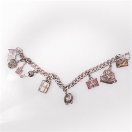 Sterling Silver Charm Bracelet: A vintage sterling silver charm bracelet. A thick sterling rope chain bares nine distinct charms embellished with enamel throughout. Charms such as a letter address to Bea, a clipper ship, American flag and a bible that opens to share scripture are part of this classic jewelry experience. Each piece is marked to reverse. The total approximate weight inclusive of all materials is 1.025 ozt.
