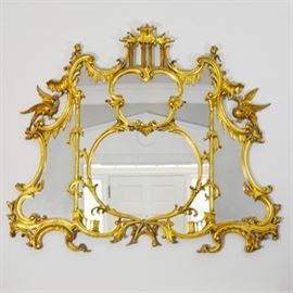 Rococo Style Gilt Wall Mirror: A Rococo style ornate gilt wall mirror. This mirror features a multi-panel design, with draping swag style detailing, leaves, columns, and birds.