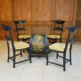 Glass Top Dining Room Table and Four Arhaus Rush Seat Chairs: A glass top dining room painted wood pedestal table and four black Arhaus rush seat side chairs. This table features a dramatic black fruit harvest painted base, with a scalloped top edge, over a four sided base below. The round glass top surface allows for a view of the base below. It includes four black Arhaus rush seat side chairs, designed with a horizontal splat back.