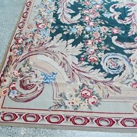 Very Large Aubusson Style Needlepoint Area Rug: A very large Aubusson style needlepoint area rug. This tapestry style rug features a center lobed medallion with sweeping florals and foliage, and classical motifs. The design features rose clusters and swags scattered across hunter green and oatmeal fields, and is detailed an narrow oval border design. The area rug is finished in tones of hunter green, oatmeal, taupe, cranberry, rose, and gray.