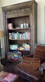 Over sized carved book case. Games, DVDs and more. One of a pair of distressed leather easy chairs