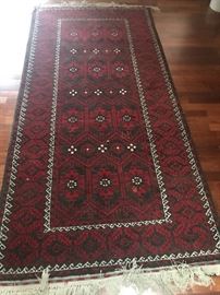 hand done rug. predominant rich red and black colors
