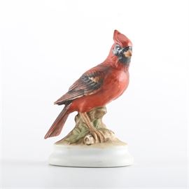 Hand-Painted Porcelain Cardinal Figurine From Lefton: A hand-painted porcelain cardinal figurine. The red bird with black shading to the beak and feathers is posed on a round pedestal decorated with leaves and branches. The piece is marked underneath “Lefton China – Hand Painted – Cardinal (Head Up) – KW 395”.