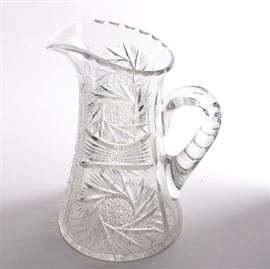Crystal Pitcher: A crystal pitcher. This pitcher features a pinched lip and curved handle with decorative body. There are no visible maker’s marks.