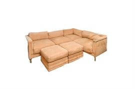 Mid Century Modern Style Suede Sectional Couch and Ottomans by Mirage: A Mid Century Modern style suede sectional couch and ottomans by Mirage. This collection features straight back and arms over panel design with short cushion back and oversized cushion seats, upholstered arm fronts and seat supports, rising up on chrome finished tube legs. Also included is a pair of coordinating square top ottomans with large cushion top and upholstered sides which mimic the design of the couch. There is a tag attached to the couch which reads “Mirage”.