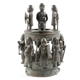 African Brass Sculpture: An African brass sculpture. The piece, which is likely a Benin ancestor altar, has two tiers on a circular base. Three figures stand on the top level and a row of seven figures stand on the lower level facing out. All are carrying weapons and several have shields.