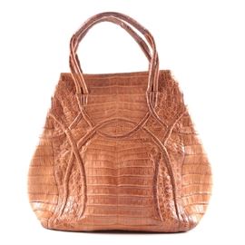 Nancy Gonzalez Crocodile Handbag: A Nancy Gonzalez genuine crocodile handbag. This brown leather bag features a loose hobo shape and doubled twisted handles stitched to each side of the bag. The interior is finished in light tan suede with crocodile leather accents along the zipper and openings of the interior pockets. The bag is labeled “Nancy Gonzalez Colombia New York” and “Genuine Crocodile Made in Colombia”.