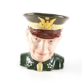 Barrington Dwight Eisenhower Ceramic Mug: A Barrington Dwight Eisenhower ceramic mug. This mug depicts Ike in his Army uniform with the bald eagle seal to the font of the hat and the stars to the shirt collar. A handle extends from the back of the hat to the back of the shirt. The underside of the mug is marked, “Barrington Made in England” and states that this ceramic mug is number 1444 of 2,000 issued.