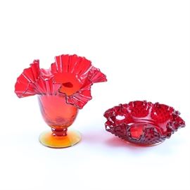 Art Glass Vessels Featuring Blenko: A pair of art glass vessels. This includes a Blenko red and orange vase with ruffled trim and a tapered body. There is also a Fenton red bowl with a ruffled edge and hobnail designs.