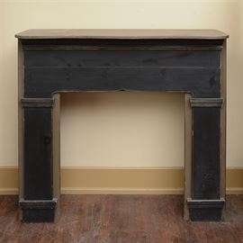 Painted Pine Mantel: A painted pine wood mantel. This piece is painted tan and black and features a scalloped shelf. The header below is embellished with crown molding and the piece has squared columnar legs.