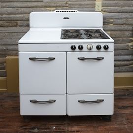 Vintage Estate Heatrola Gas Stove: A vintage Estate Heatrola gas stove. This double oven appliance features four eyes for cooking, a blank space next to the eyes, two ovens, and beneath those, two drawers. One of the ovens has solid sheets, the other, slotted racks. A central white knob for the oven is centered between the black knobs controlling the eyes. To find out more about the Estate Company which was based in Hamilton, Ohio, please see the link in the additional information below.