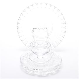 Assorted Crystal Glassware: A collection of assorted crystal glassware. This selection features two Waterford crystal plates, one with a starburst pattern at the center and a dimpled edge and the other with a multi pattern border. Also included is a cup and plate with a diamond shaped pattern around the bowl.