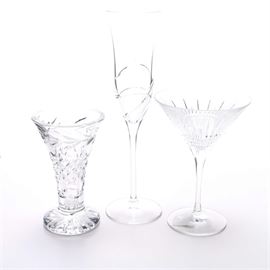 Waterford Crystal Barware: A collection of three Waterford crystal barware pieces. This crystal collection includes a port wine glass with a botanical motif, quilted pattern, and starburst bottom, a Champagne flute with a linear pattern, and a starburst martini glass. The Waterford trademark label is displayed to the base of each piece.
