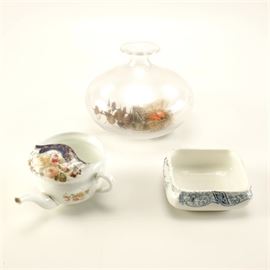 Décor Including Antique Doulton Burslem China and Invalid Feeder: An assortment of glass and ceramic décor. This collection features a square dish in the Warwick pattern by Doulton Burslem, with a mark dating to circa the late nineteenth century, which is missing its lid. Also included are a floral invalid feeder and a round clear glass terrarium with a faux birds’ nest inside.