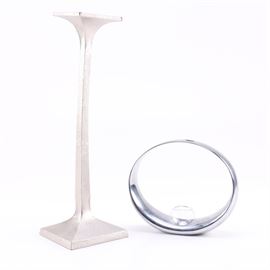 Donna Karan for Lenox "Burnished Metal" Candlestick and Nambé Candle Holder: A Donna Karan for Lenox Burnished Metal candlestick and Nambé candle holder. This selection includes a tall metal candlestick with a texturized finish, marked to its underside “Dona Karan Lenox” and “Donna Karan Burnished Metal Small Candlestick Made in India”. Also included is a Nambé candle holder which is presented with a metal open ring featuring a glass sconce resting in a central piercing on its lower portion. This piece is marked to its underside “Nambé MT0038 2009 Neil Cohen”.